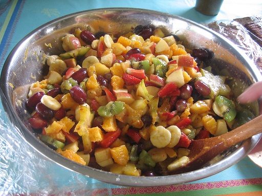 fresh fruit salad in a silver mixing bowl with wooden spoon