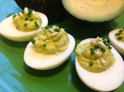 Avocado Deviled Eggs lined up on a green ceramic plate