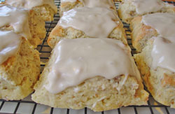 many frosted cream cheese walnut scones cooling on a rack