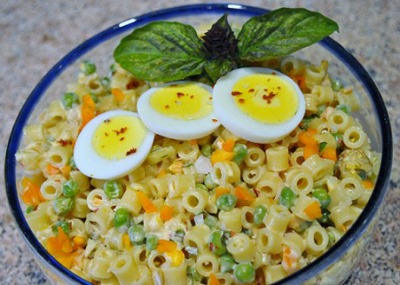 Ditalini Pastai Salad in a glass bowl garnished with slices of hard boiled eggs
