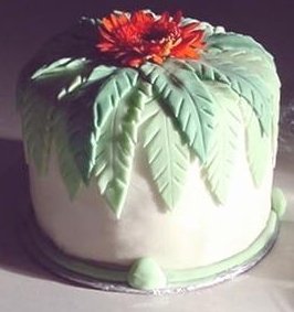 a tall round cake decorated with a red flower and green leaves
