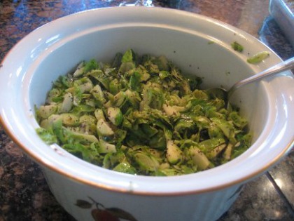 Hashed Brussels Sprouts in a deep white dish with a spoon on top of a counter