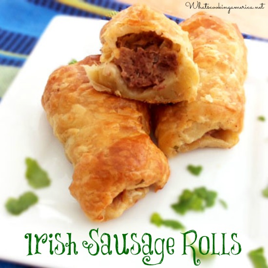 Three Irish Sausage Rolls with flaky crusts on a cutting board.