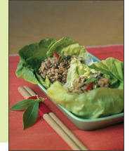 a long narrow plate of chicken lettuce wraps and a set of chopsticks on a red table