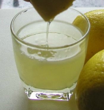 lemons being juiced into a glass cut
