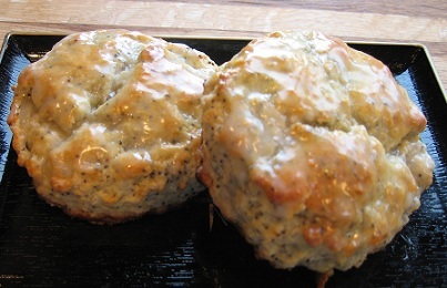 two Orange Poppy Seed Scones on a square black plate