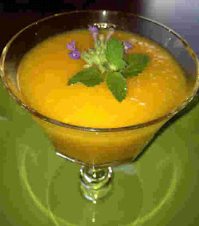 Mango Soup or Smoothie served in a cocktail glass with garnish on a green table