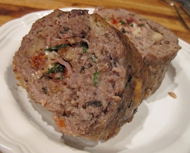 Prosciutto-stuffed Meatloaf cut in half on a white plate