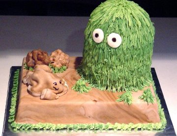 a sheet cake decorated with a large grass character and his pet rock made from fondant