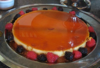 Spanish Orange Flan on a metal serving plate decorated with raspberries and blackberries