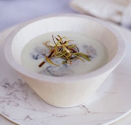 oyster soup with frizzles leeks served in a white bowl on a white marble plate