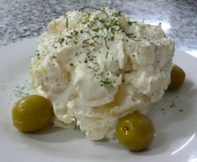 Spanish Potatoes on a white plate with green olives