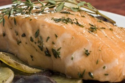 close up image of Poached Salmon topped with rosemary and garnished with lemon slices
