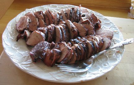 Pork Tenderloin cut up on a white plate with a fork