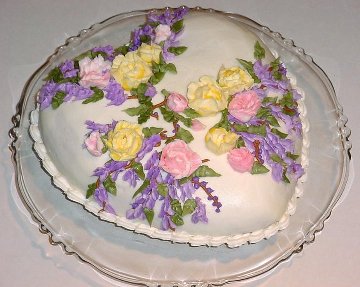 white heart shaped cake decorated with spring flowers on a cake tray