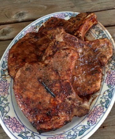 Spiced Grilled Pork Chops on a large decorated plate staged on a picnic table