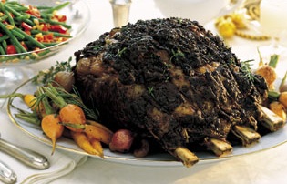 Standing Rib Roast with rosemary-thyme crush on a serving dish with vegetables