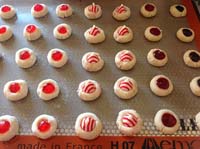 Unbaked thumbprint cookies decorated and lined on a baking pan ready to go in the oven.