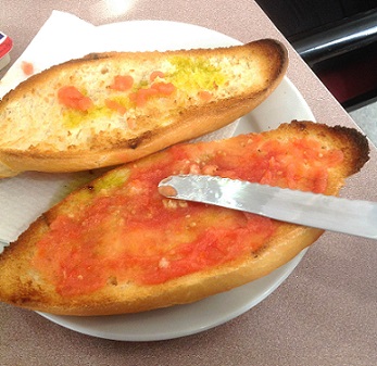 Spanish Toast on a plate being spread with tomato