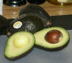 Halved Avocado on a counter top with whole avocados in the background