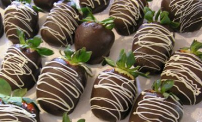 close up image of chocolate strawberries on parchment paper, some drizzled with white chocolate