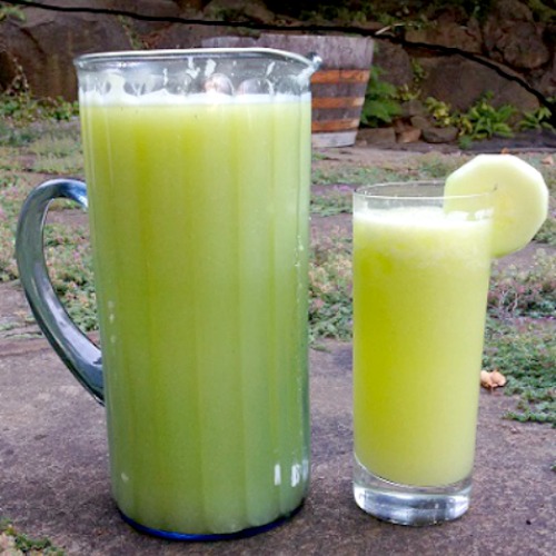 Cucumber Zucchini Aqua Fresca in a pitcher next to a cup with cucumber on the rim 