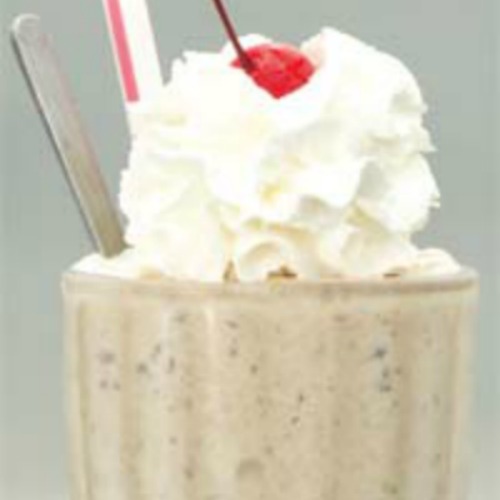 Tall glass of date shake topped with whipped cream and cherry