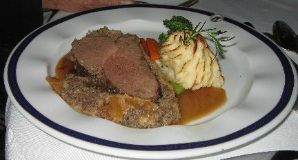 Beef Wellingtons on a white plate with sides and garnish