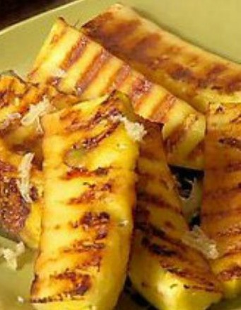 close up image of grilled pineapple slices in a lime green bowl