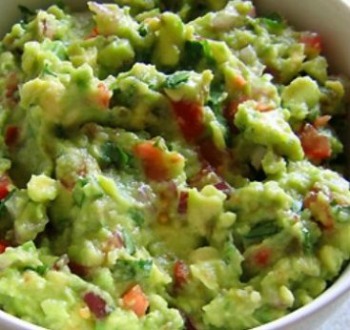close up image of chunky homemade guacamole in a bowl