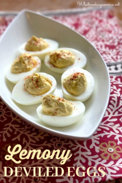lemony deviled eggs arranged on a white ceramic boat shaped serving plate