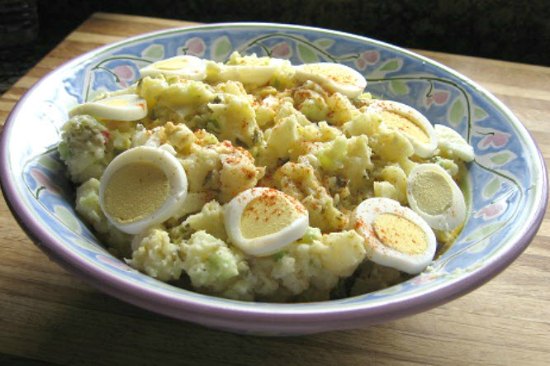 large bowl of potato salad topped with paprika and slices of hard boiled egg