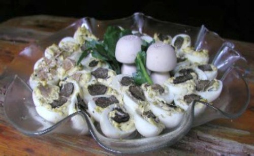 Deviled Eggs With Truffles sliced in half and served in a glass serving dish