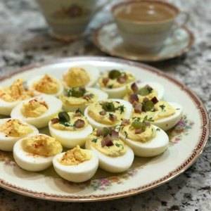 deviled eggs arranged on a tan plate with a tea cup in the background