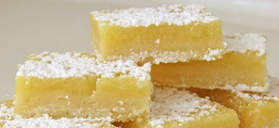 Lemon Bars dusted with powdered sugar and stacked in a pile.