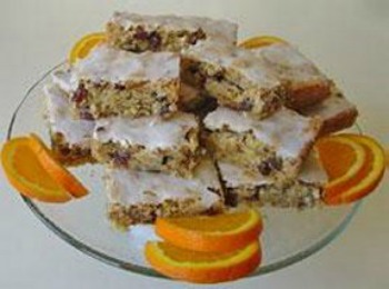 Orange Date Nut Bars arranged on a cake stand and garnished with orange slices