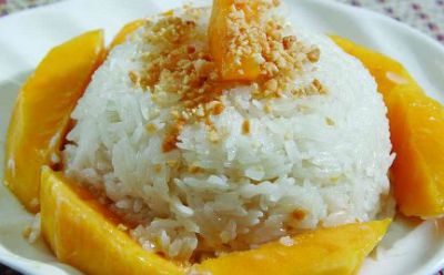 ball of sticky rice surrounded by mango slices with mango on top as garnish