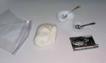 fondant dough, ziplock bag, foil, and spoons on white counter