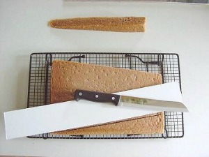 sheet cake with paper and knife on top of a wire cooling rack