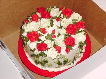 round cake decorated with red and white roses sitting in a box
