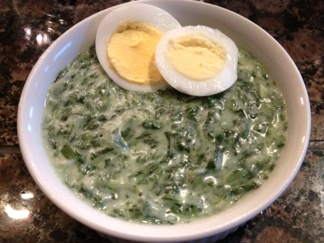 German Creamed Spinach in a white bowl with two slices of hard boiled egg as garnish