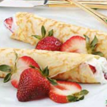 strawberry lime crepes on a white plate with strawberry slices