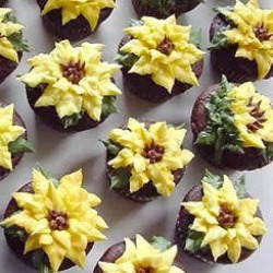 many cupcakes decorated with sunflowers in rows on a white surface