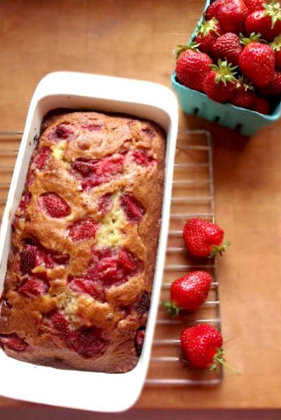 Strawberry Banana Bread in a baking dish and cooling rack next to a bowl of strawberries