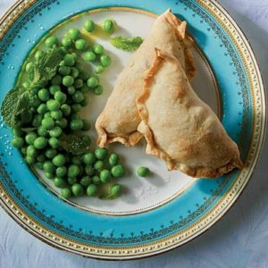 Cornish Pasties next to peas on a plate